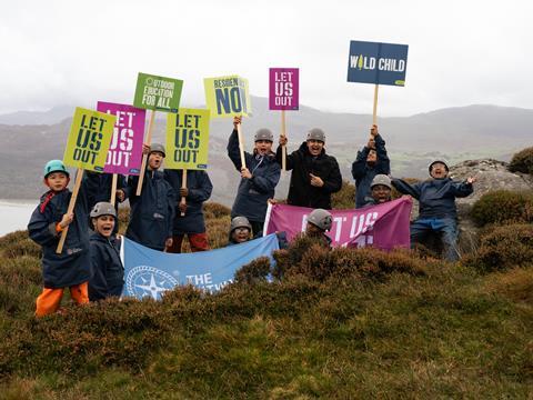 A group of young people hold banners and flags supporting the Let Us Out campaign to make outdoor residentials part of the school curriculum