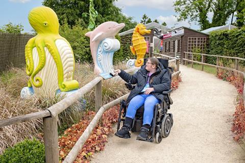 A girl in a wheelchair pushes a button on an interactive display