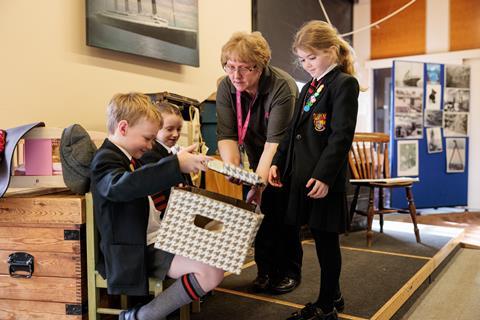 A woman hands a group of school children a cardboard box