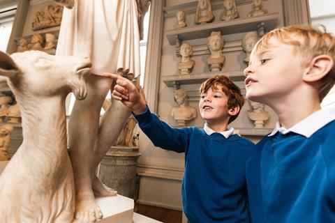 Two young boys look at a statue of a goat