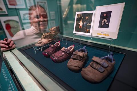 Young woman looking into display case containing old shoes